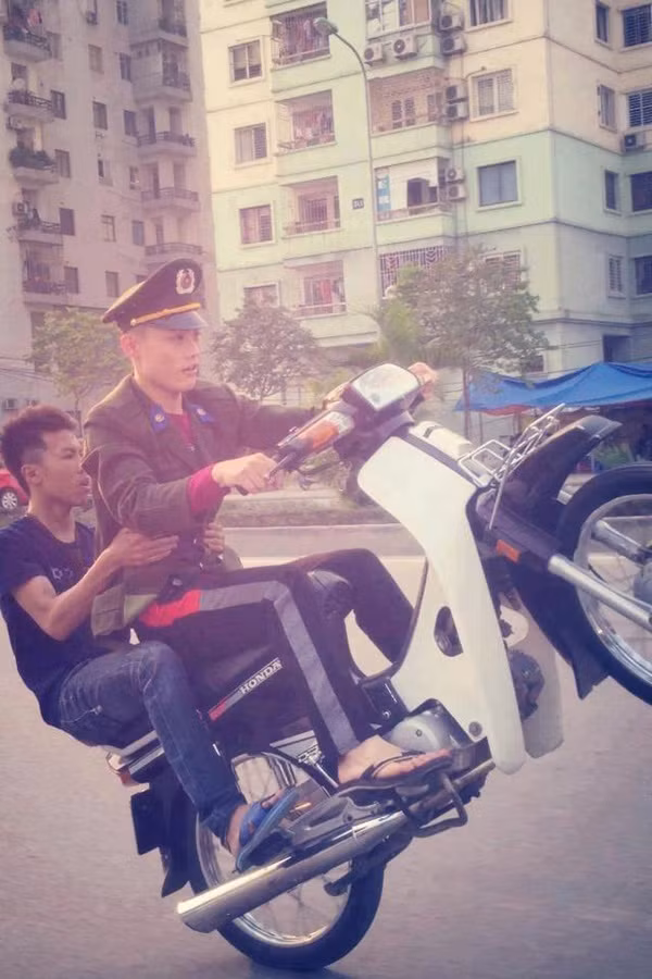 Một nam thanh niên mặc cảnh phục, đèo bạn bốc đầu xe cực kỳ phản cảm.