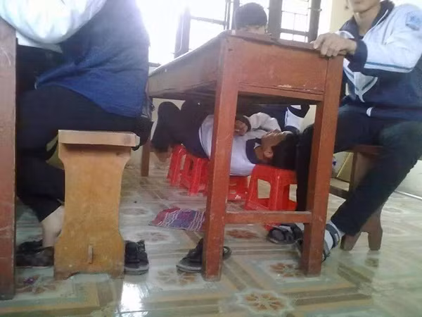 Nam sinh trốn dưới gầm bàn để ngủ gục.