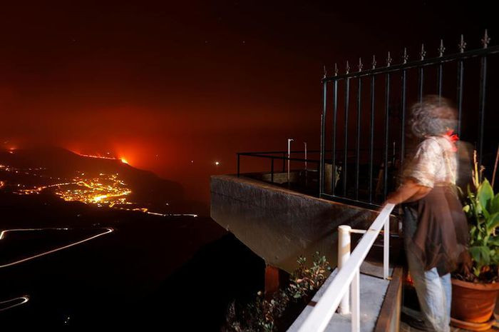 Một phụ nữ sống tại thị trấn Tijarafe chiêm ngưỡng cảnh tượng dung nham tràn ra biển, đêm 28/9.