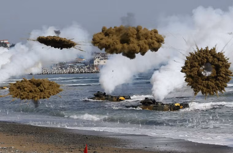 Trong ảnh là khoa mục tập trận đổ bộ đánh chiếm bờ biển với sự tham gia của các "kình ngư" AAV-7 - xe bọc thép lội nước tiêu chuẩn của Lính thủy Đánh bộ Mỹ - Hàn. Trong ảnh là các xe AAV-7 phóng đạn khói gây nhiễu vũ khí dẫn đường của đối phương.