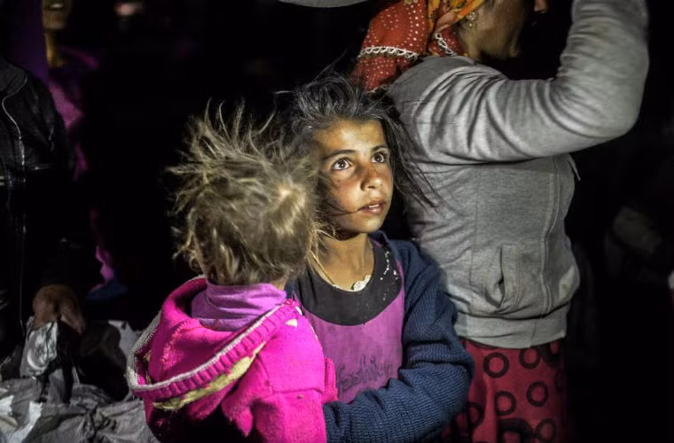 Em bé Syria bế em đi cùng gia đình đang vượt biên giới sang Thổ Nhĩ Kỳ ngày 21/9.