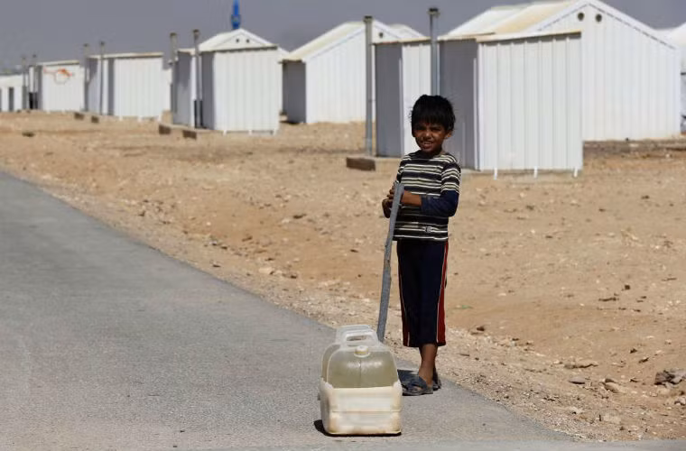 Một bé trai Syria đang đi lấy nước trong trại tị nạn.
