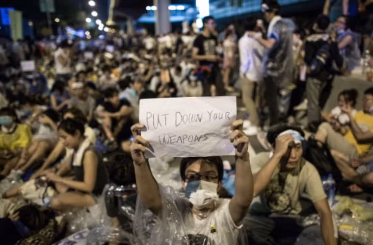 Người biểu tình giơ khẩu hiệu kêu gọi cảnh sát hạ vũ khí.