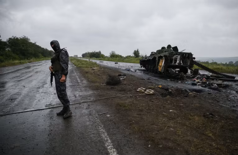 Một binh sĩ Ukraine đứng bên cạnh một xe bọc thép của lực lượng ly khai bị tiêu diệt gần Slavyansk.