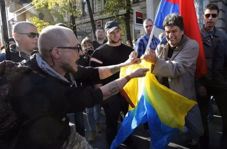 Tuy nhiên, cũng có rất nhiều người tổ chức một cuộc biểu tình khác nhằm ủng hộ phe ly khai ở Ukraine. Trong ảnh, một người biểu tình ủng hộ phe ly khai xé cờ của Ukraine.