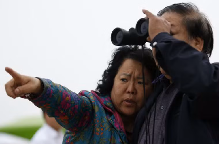 Một người ông dùng ống nhòm để tham gia tìm kiếm người cháu bị mất tích. Vào lúc 2h sáng ngày 19/4, đã có 29 nạn nhân chết trong vụ chìm phà Sewol, 174 nạn nhân được giải cứu.