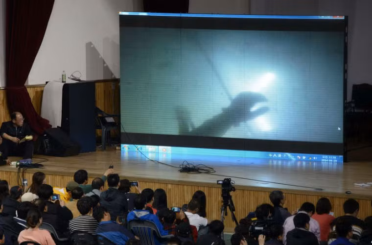 Thân nhân của các nạn nhân theo dõi trực tiếp quá trình tìm kiếm cứu nạn của thợ lặn qua màn hình lớn.