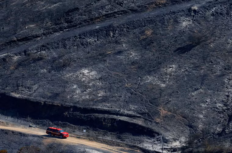 Xe của lính cứu hỏa đi qua một khu vực bị ngọn lửa cháy rừng thiêu rụi gần thành phố San Marcos.