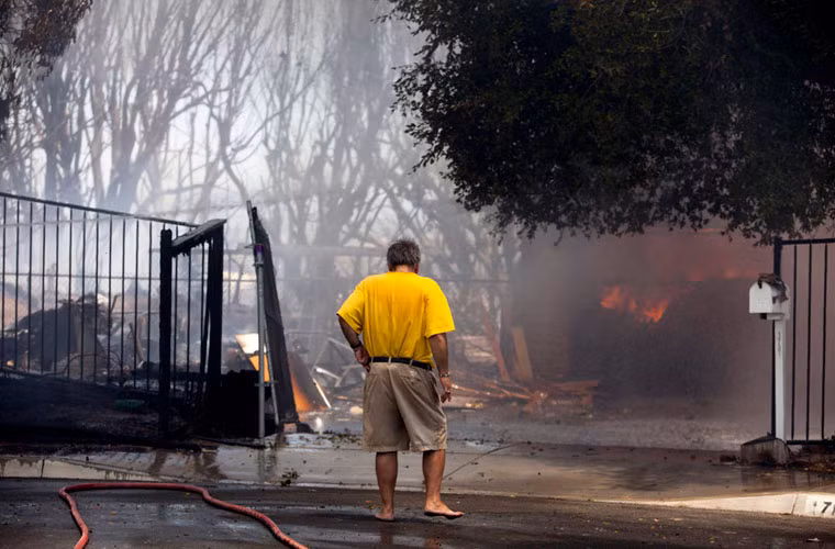 Ông Greg Saska trước đống đổ nát từng là ngôi nhà của mẹ ông trước khi bị thiêu rụi ở thành phố Carlsbad.