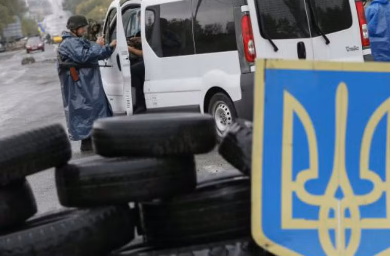 Binh sĩ Ukraine kiểm soát giấy tờ lái xe tại một điểm kiểm soát.