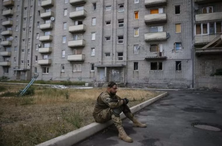 Một binh sĩ Ukraine ngồi nghỉ tại tòa nhà bị hư hỏng do chiến tranh ở Lugansk.