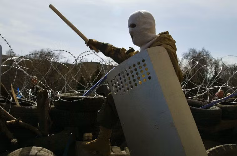 Một người biểu tình đeo mặt nạ đứng gần hàng rào thép gai được dựng lên bên ngoài tòa thị chính Donetsk vào ngày 7/4/2014.