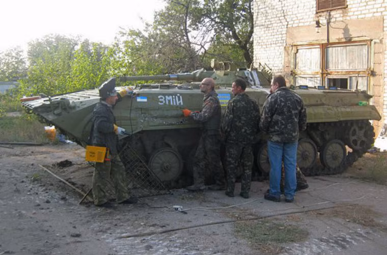 Các tình nguyện viên chuẩn bị lắp thêm lớp ráp cho xe bọc thép Ukraine.