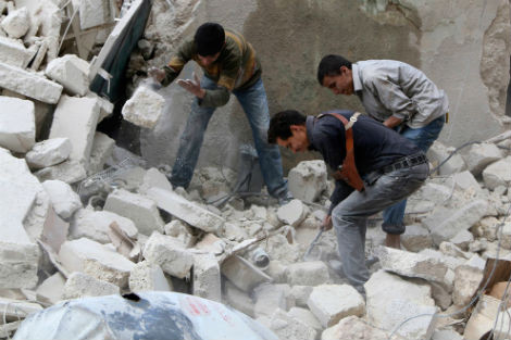 Phe nổi dậy Syria tìm kiếm người sống sót sau khi một tòa nhà trúng bom của Không quân Syria ở quận Karam, Aleppo vào ngày 26/3/2014.