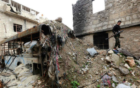 Một binh sĩ quân nổi dậy Syria đang đi trên đống đổ nát ở Ashrafieh, Aleppo vào ngày 13/3/2014.