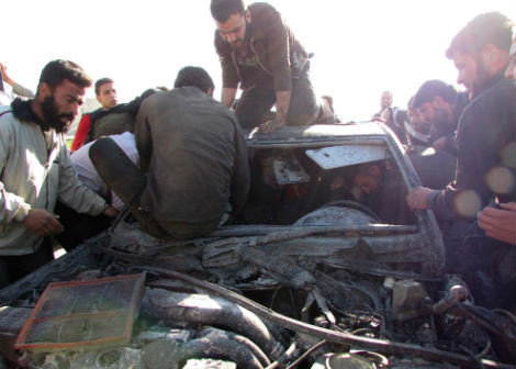 Người dân đang cố sơ cứu những người bị thương bên trong một chiếc xe hư hại do trúng bom của máy bay của quân chính phủ Syria ở ngoại ô Aleppo, ngày 26/3/2014.