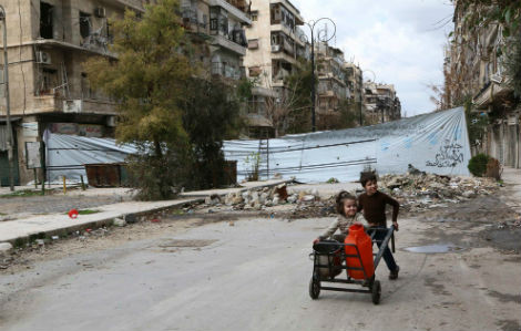 Trẻ em Syria đang đi lấy nước dọc con đường bị hư hại ở Aleppo vào ngày 11/3/2014. Số trẻ em bị ảnh hưởng bởi cuộc nội chiến Syria đã tăng lên gấp đôi kể từ năm 2013.