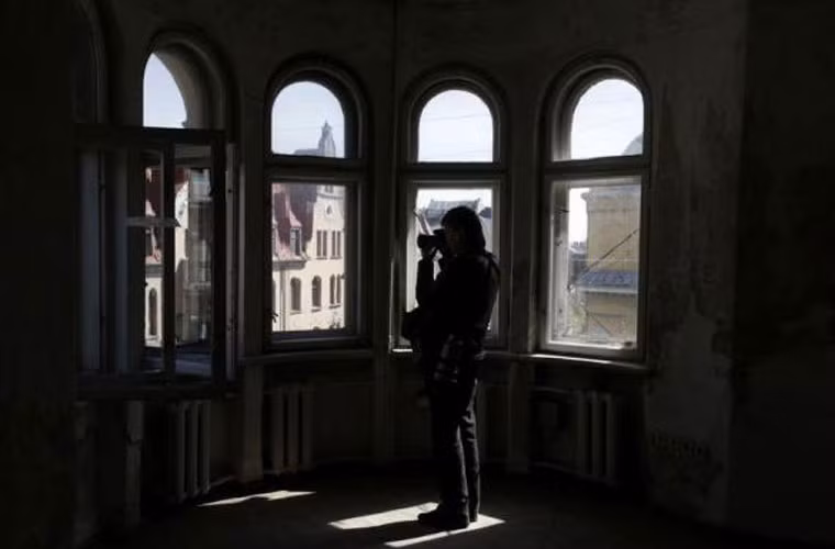 Một nhiếp ảnh gia khác đang chụp ảnh khung cảnh bên ngoài từ bên trong tòa nhà trụ sở cũ của KGB tại Latvia.