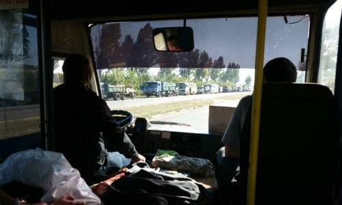 Một đoàn xe quân sự đi qua chuyến xe buýt.