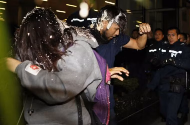 Người biểu tình rút lui trước các bình xịt hơi cay của cảnh sát.