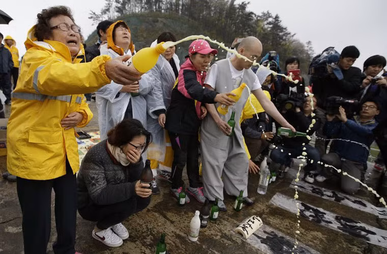 Nhiều người tham gia cầu nguyện cùng một nhà sư cho những hành khách mất tích tại bến cảng Jindo.