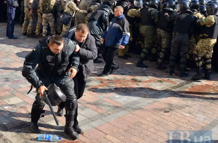 Một cảnh sát bị thương được dìu đi.