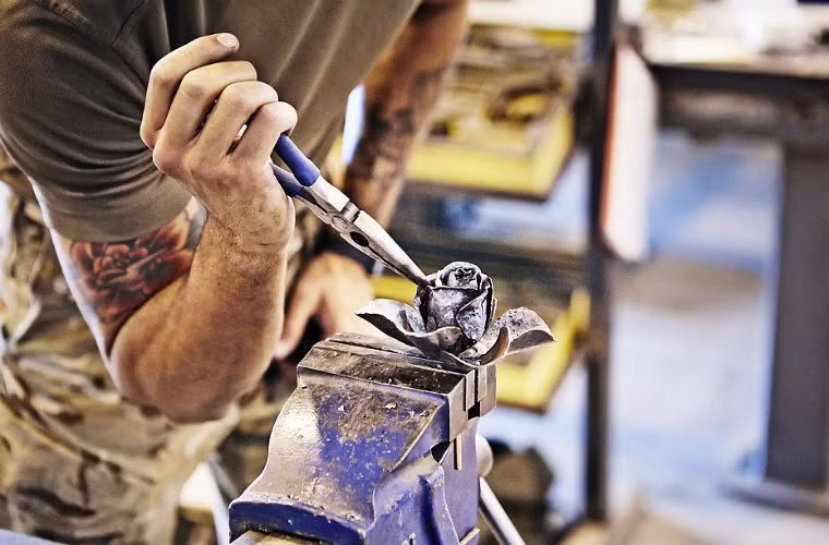 Trong khi đó, một người lính đang khắc một bông hồng bằng kim loại để gửi về nhà.