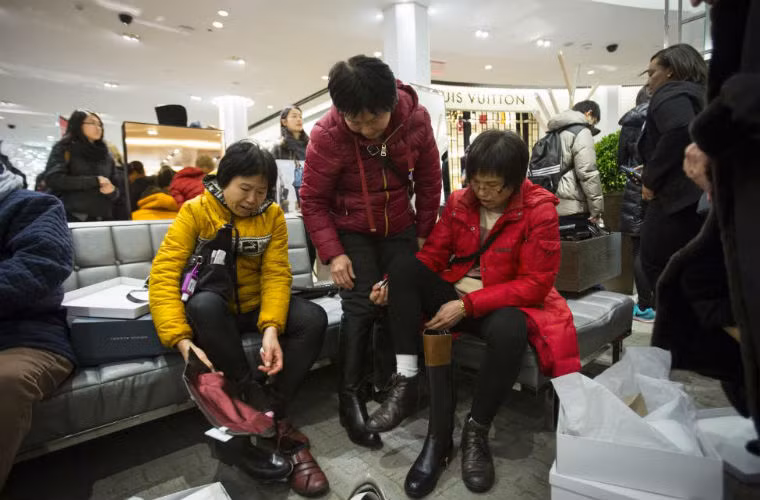 Những vị khách thay nhau thử những đôi giày được giảm giá ở chuỗi siêu thị Macy's.