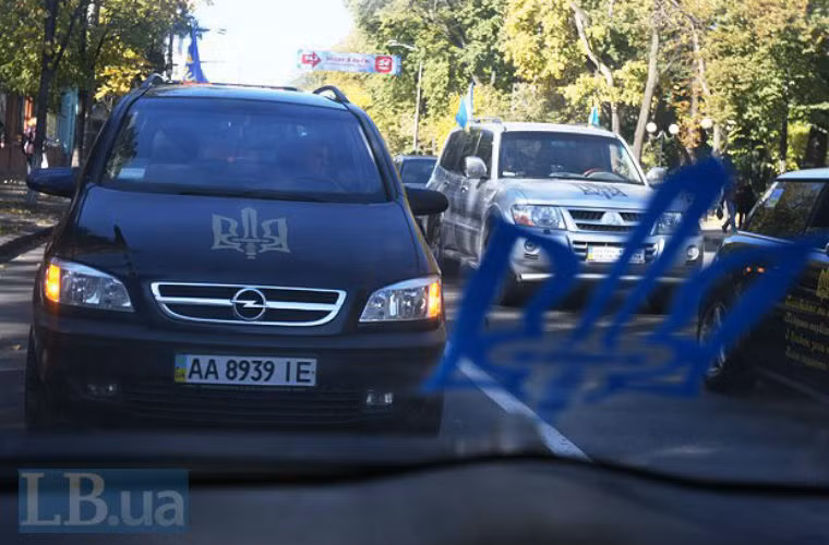 Người biểu tình sơn lên xe đỗ trước tòa nhà.