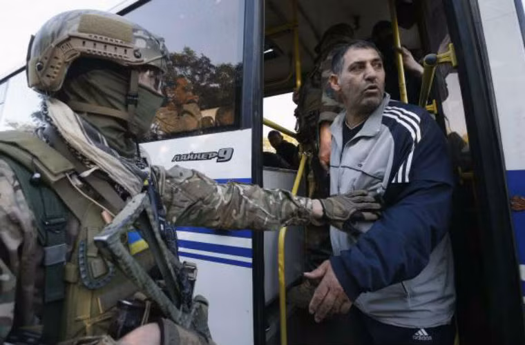 Binh sĩ Ukraine hướng dẫn tù nhân được trao trả xuống xe.