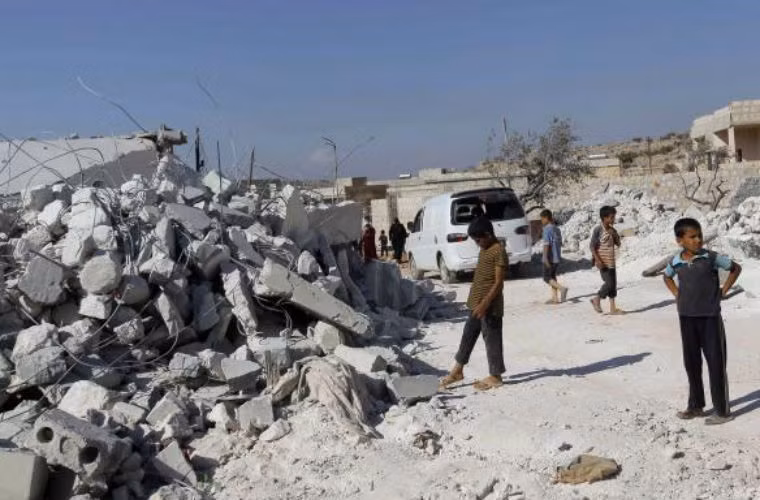 Người dân Syria trước ngôi nhà bị máy bay Mỹ ném bom phá hủy.