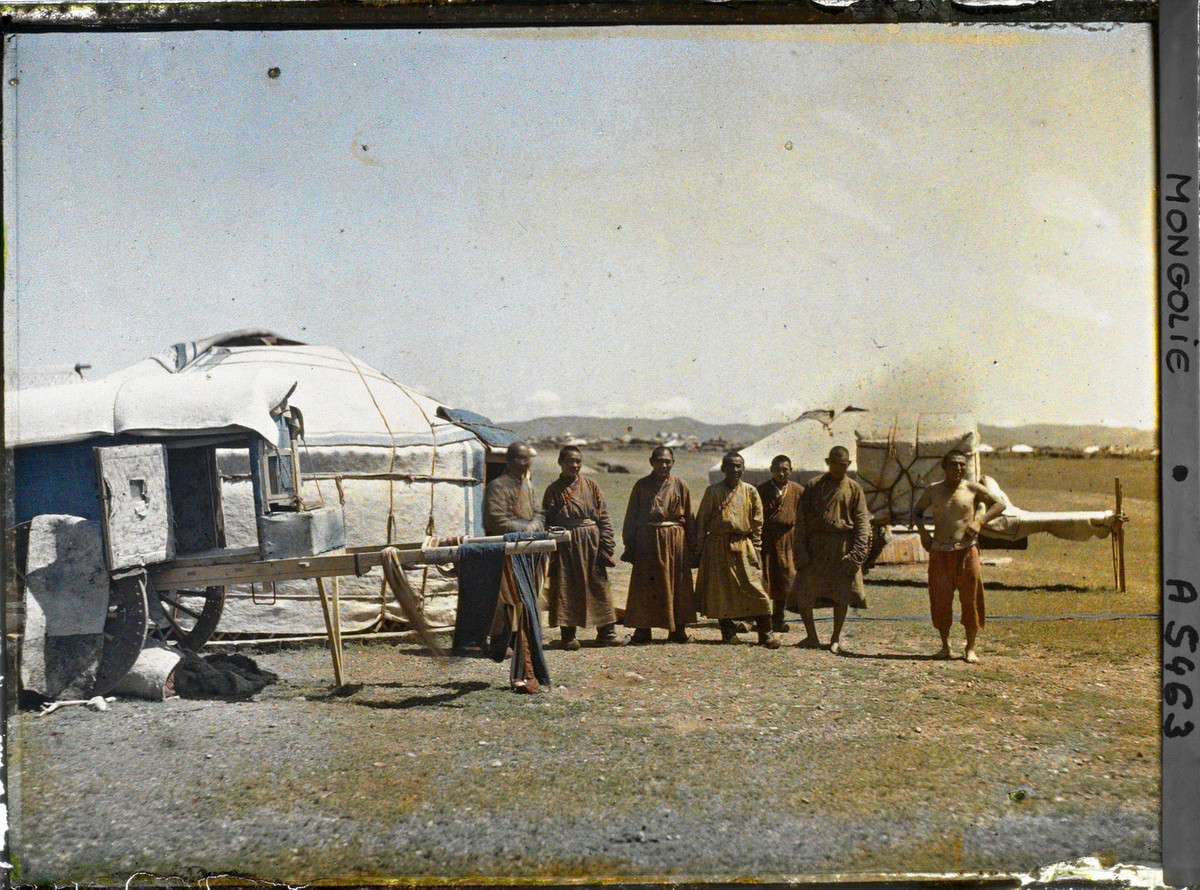 Nhóm lạt ma trẻ đứng gần một lều yurt và những chiếc xe kéo bằng gia súc.