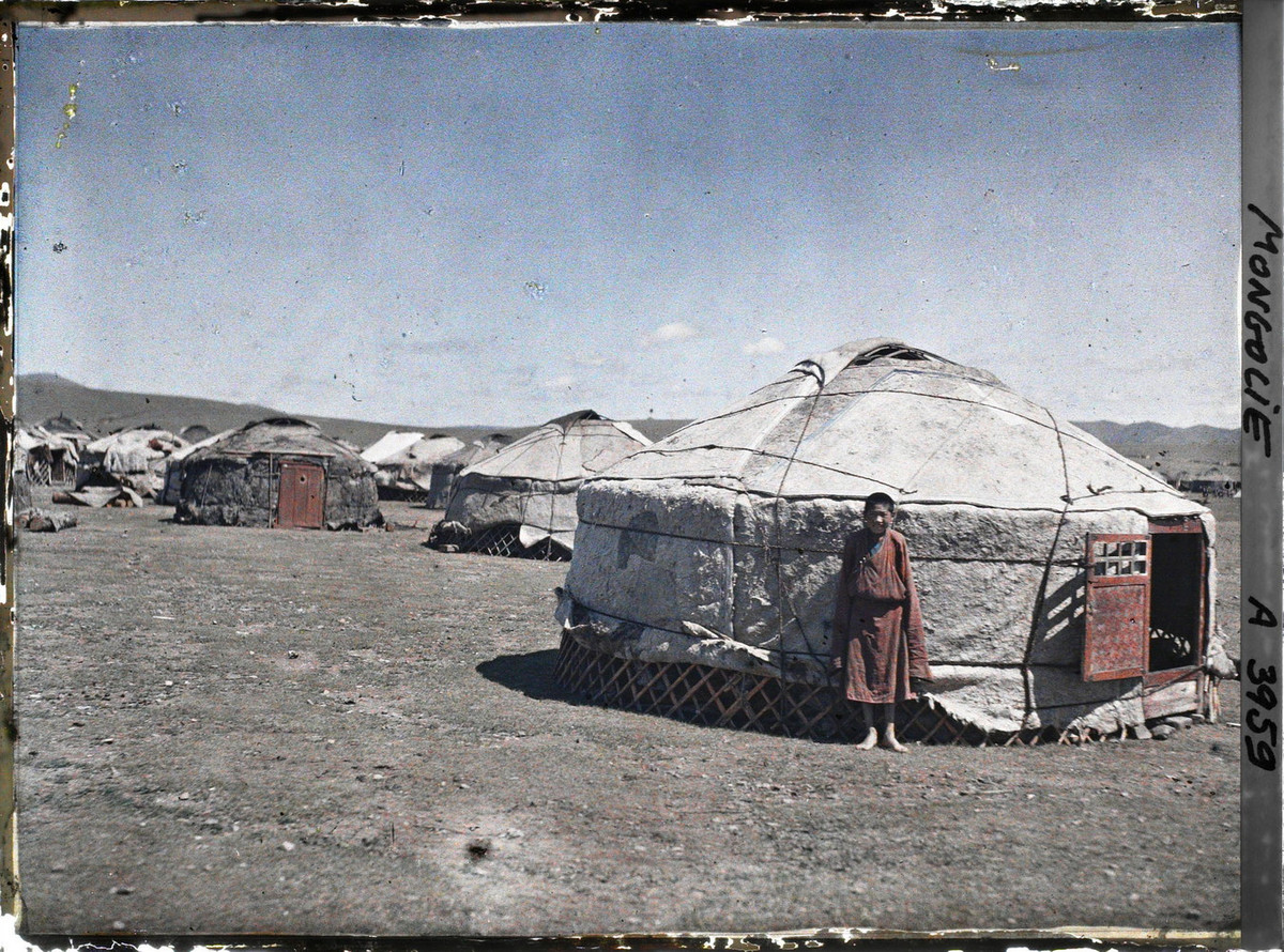 Một thiếu niên đứng dựa vào lều yurt.