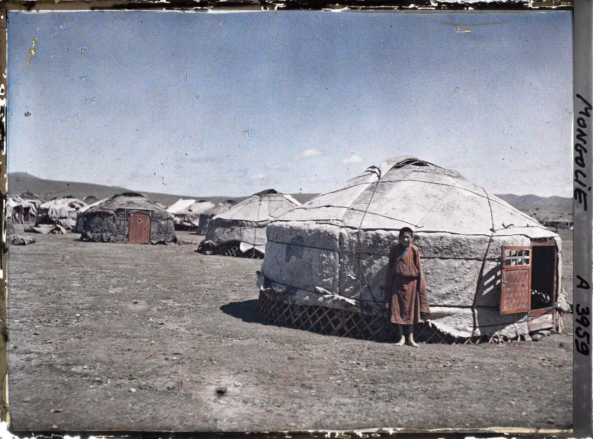 Một thiếu niên đứng dựa vào lều yurt.