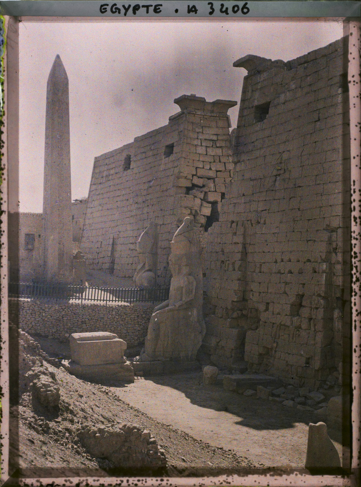 Lối vào chính của đền Luxor nhìn từ bên phải, Ai Cập năm 1914. Khu vực này có hai bức tượng của pharaon Ramesses II và hai tháp đá obelisk. Một trong hai tháp obelisk đã bị mang về Paris, chỉ còn lại bệ cột. Ảnh: Auguste Léon / Collections.albert-kahn.hauts-de-seine.fr.