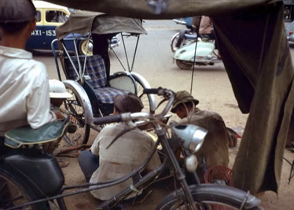 Một chiếc xích lô được sửa chữa dưới lòng đường.