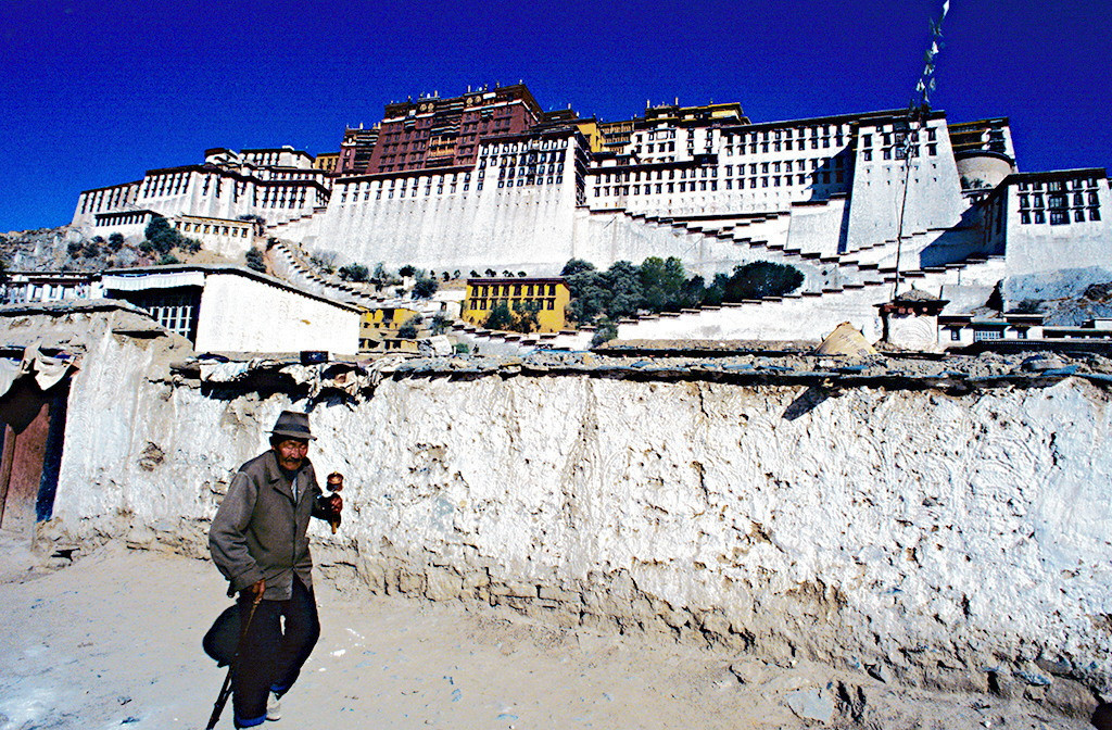 Người đàn ông cầm bánh xe cầu nguyện đi qua khu vực cung điện Potala.