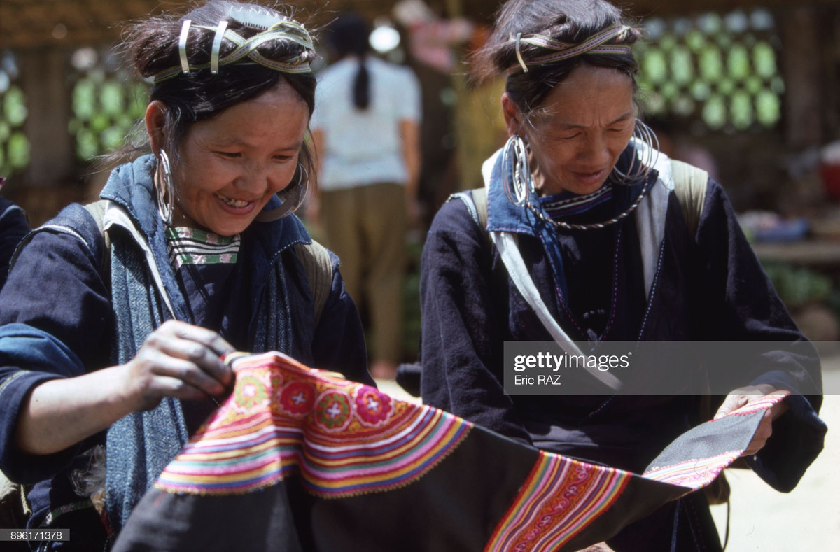 Hai phụ nữ đồng bào H'Mông xem xét tấm vải thổ cẩm ở chợ Sa Pa.