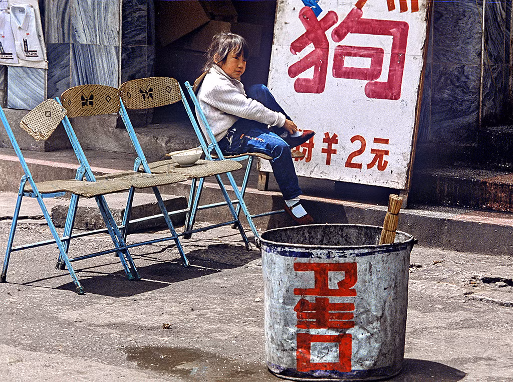 Bá gái Vân Nam ngồi bên ngoài một cửa hàng.