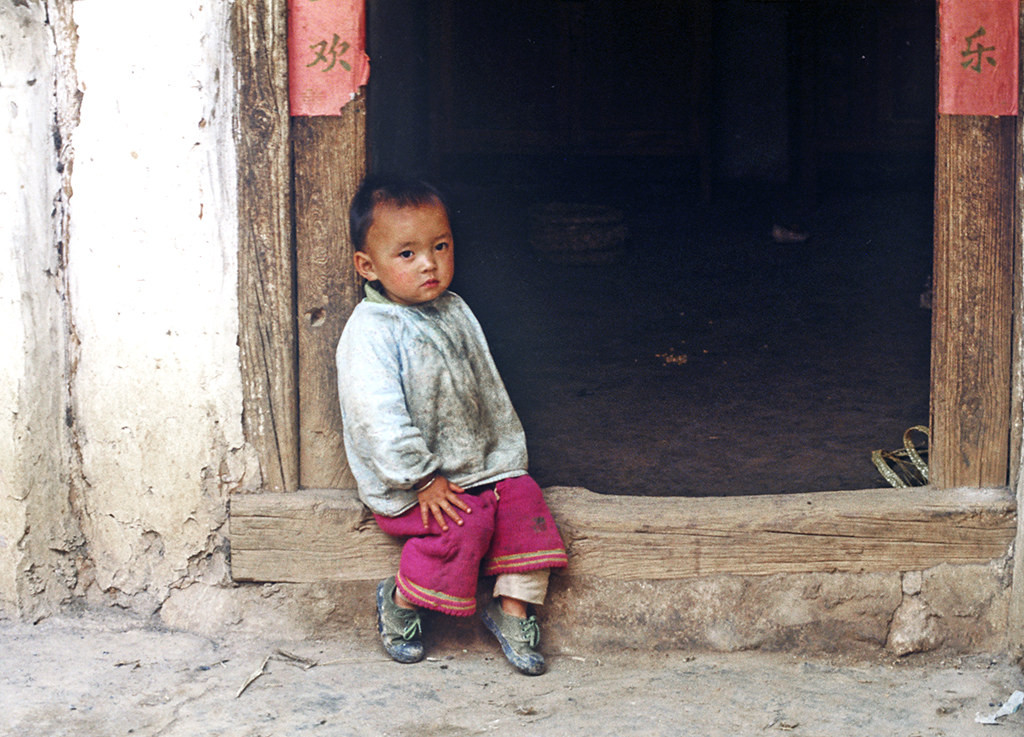 Cậu bé ngồi trên bậc cửa.