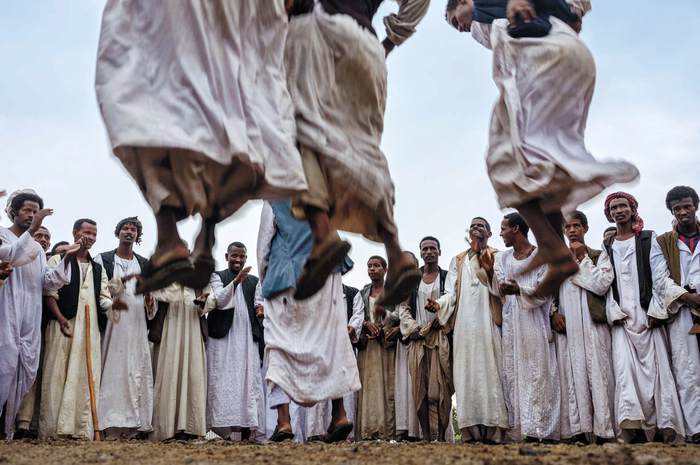 Ảnh chụp tại Sudan, 2020. Bức ảnh được chụp tại một đám cưới diễn ra tại khu vực thuộc dãy núi Biển Đỏ (Red Sea). Trước đó, trời đổ mưa. Khi mưa tạnh, người tham gia đám cưới bắt đầu thực hiện các điệu nhảy. Những người đàn ông sẽ bật nhảy và thi xem ai nhảy cao hơn. Nhiếp ảnh gia Nichole Sobecki ấn tượng bởi sự tử tế và nhiệt tình của những người lạ tại đây.