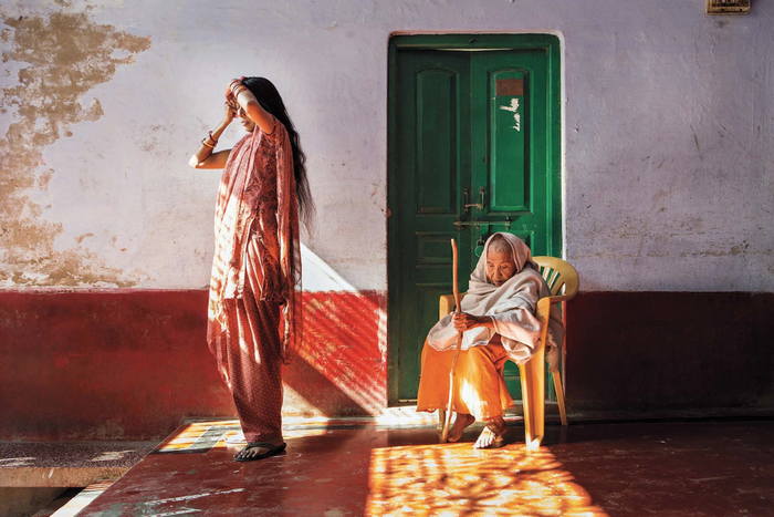 Ảnh chụp tại Ấn Độ, 2013. Vrindavan, thành phố ở miền Trung Ấn Độ, được mệnh danh là “thành phố của những góa phụ”. Theo truyền thống văn hóa tại đây, người phụ nữ góa bụa phải cắt tóc ngắn và quấn khăn trắng. Bà Lalita, ngồi ở góc phải là một ví dụ điển hình. Tuy nhiên những góa phụ trẻ ít bị ràng buộc bởi các phong tục truyền thống hơn. Trong rất nhiều trường hợp, sự ra đi của người chồng đồng nghĩa với việc người vợ rơi vào cảnh bị ngược đãi và đày đọa bởi phong tục truyền thống, nhưng những người phụ nữ đang bắt đầu đứng lên phản kháng.