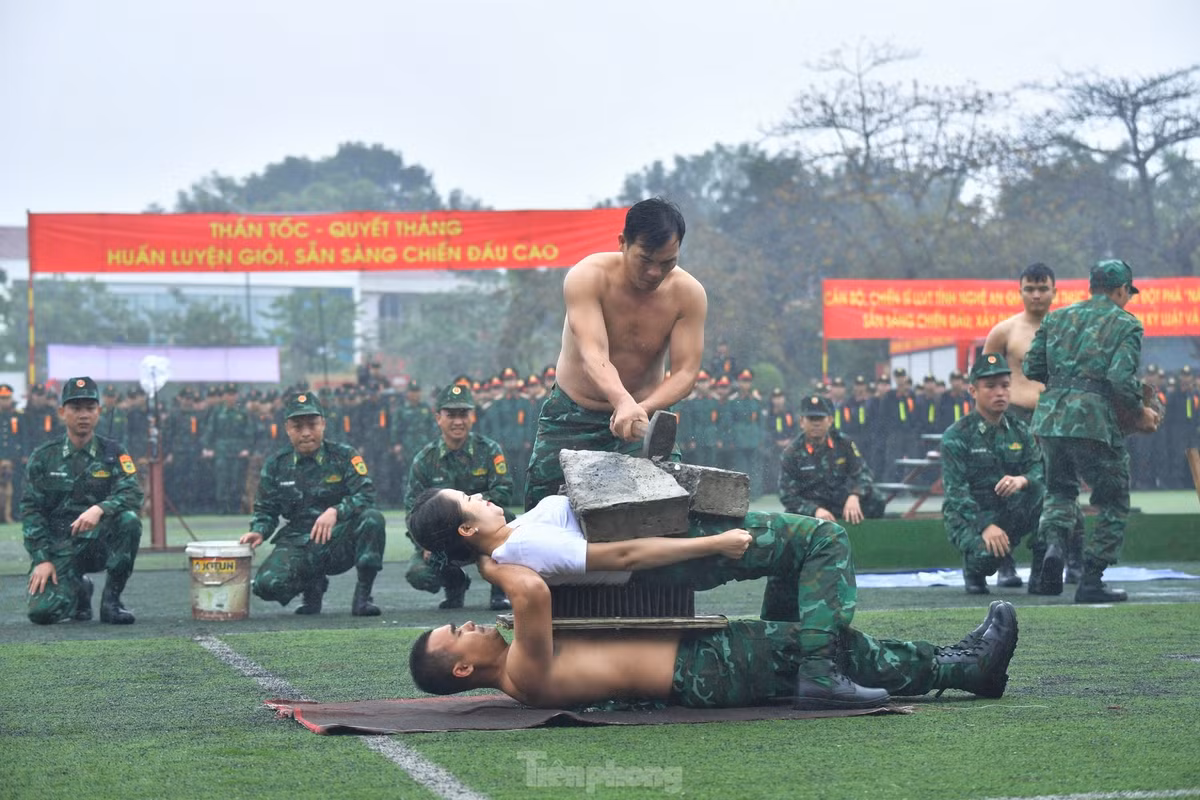 Hai cán bộ Biên phòng nằm trên thủy tinh vỡ, trên bàn chông để đồng đội dùng búa tạ đập vỡ tảng đá trên người.