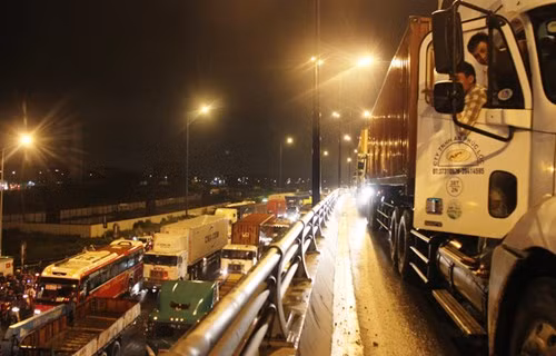 Cây cầu thép run bần bật vì gánh lượng xe tải, container chết gí trên cầu. Cánh lái xe trên cầu bất lực nhìn giao thông hỗn loạn, không có lối thoát.