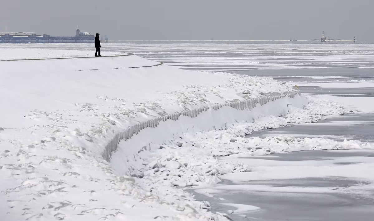 Một người đàn ông đứng nhìn về phía hồ Michigan ở Chicago bị đóng băng vì bão tuyết.
