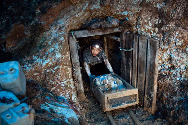 Người thợ trẻ tuổi đẩy thùng quặng ra khỏi đường hầm. Hơn 15 triệu người, trong đó xấp xỉ 3 triệu là trẻ em và phụ nữ, tham gia vào ngành này ở 70 quốc gia khắp nỏi trên thế giới.