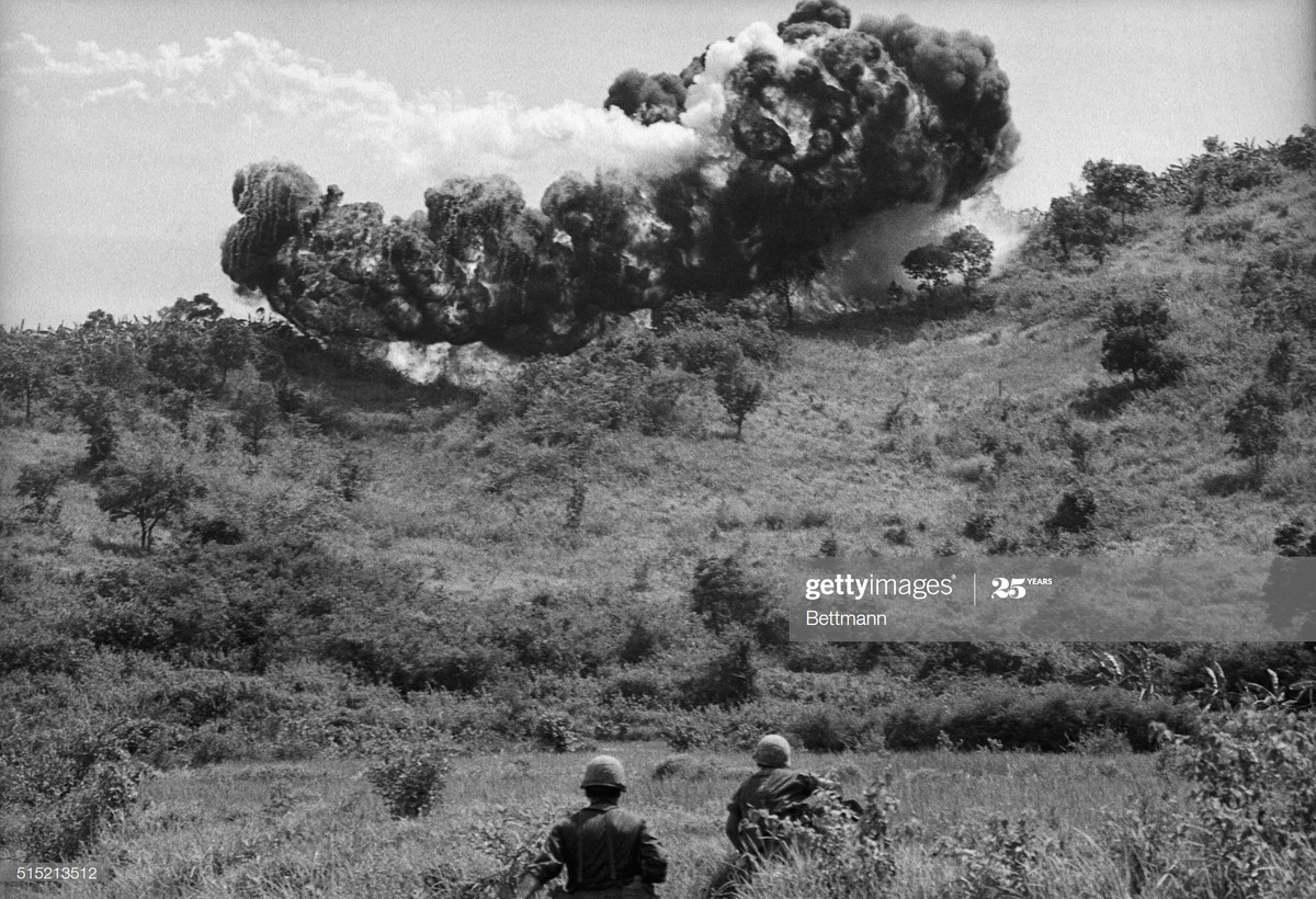 Hai binh sĩ Mỹ của Sư đoàn Dù 101 đứng gần địa điểm bom napalm phát hỏa trên chiến trường An Khê, Bình Định, 15/9/1965.