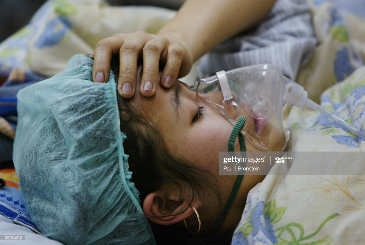 Y tá dùng tay kiểm tra nhanh nhiệt độ cơ thể của một bệnh nhân cúm gia cầm, 22/1/2004.