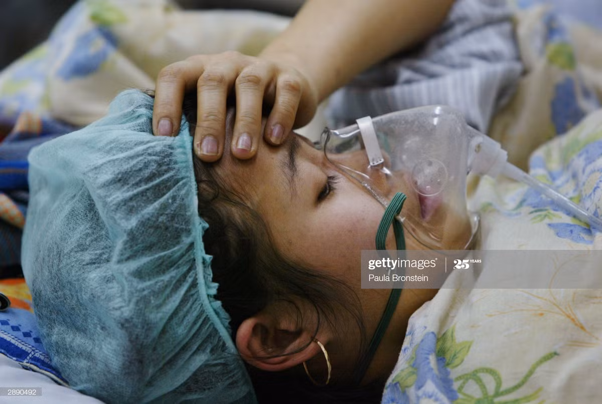 Y tá dùng tay kiểm tra nhanh nhiệt độ cơ thể của một bệnh nhân cúm gia cầm, 22/1/2004.