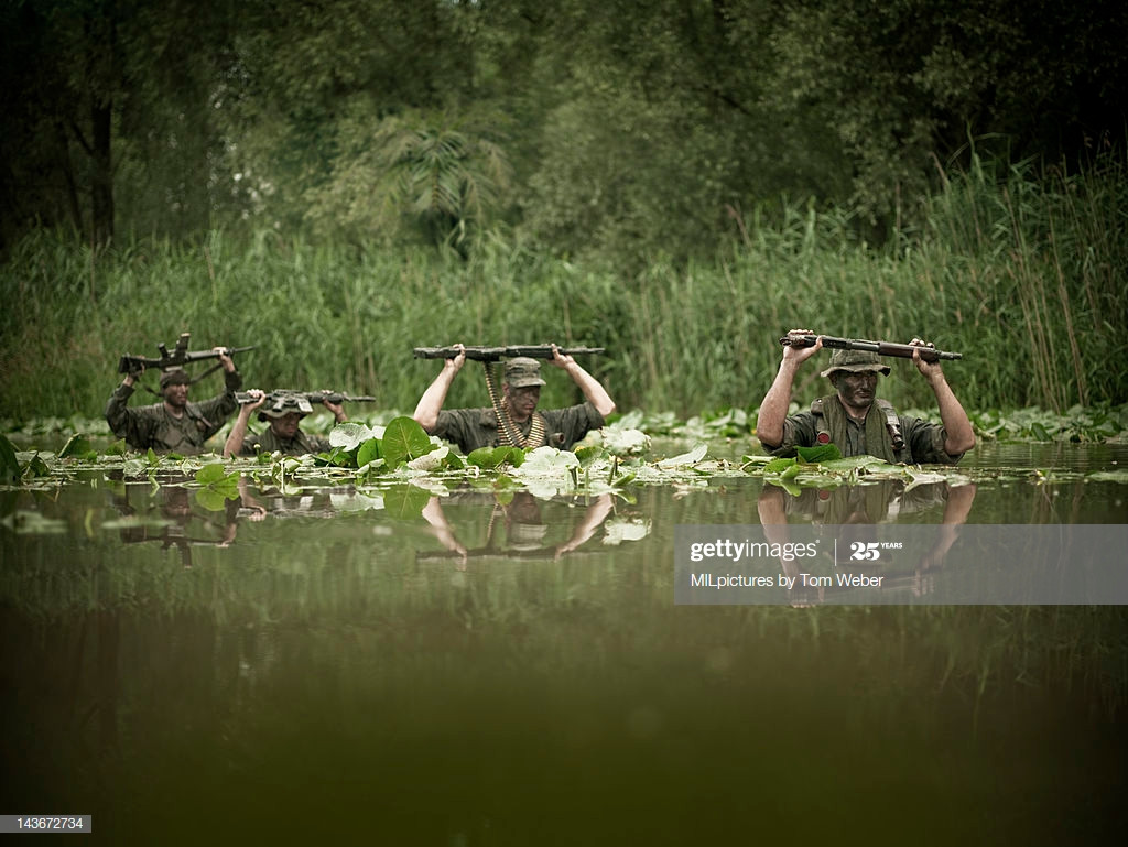 Hành quân trong đầm sen với những khẩu súng máy giơ cao quá đầu để tránh bị ướt.